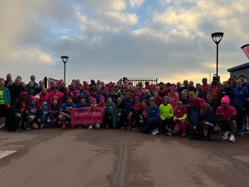 A large group of runners with a pink FordyRuns banner in front of them