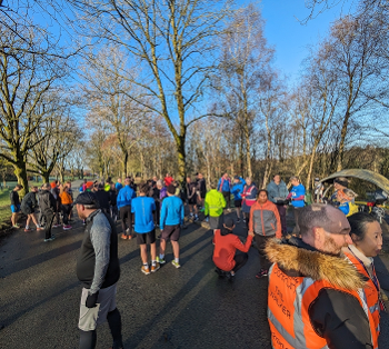 Bright blue sky, bare trees, multi-coloured runners on tarmac. The start line of a parkrun