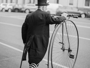 A man in fancy dress with a Penny Farthing bicycle.

Image by Eye Speak on Unsplash.