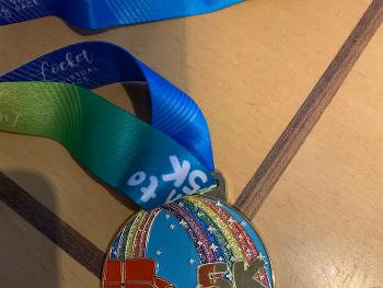Couch to 5K medal showing a rainbow leading from the couch to a pot of gold
