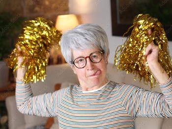 Older lady waving gold tinsel pom-poms 