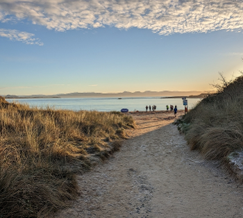 View down a sandy path to the start point of the Hafan Pwllheli parkrun at the sea shore.