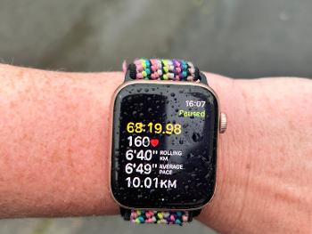 An arm wearing an Apple Watch in the rain showing 10km covered