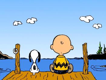 Blue sky;few clouds.  Charlie Brown and Snoopy on a dock facing a lake