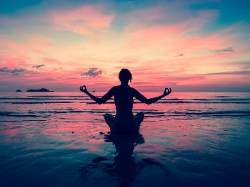 Woman on beach in peaceful yoga pose