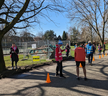 Parkrun finish funnel. It's sunny and there are tree shadows on the path.