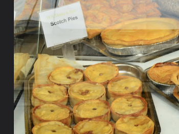 Image of an array of Scotch pies under glass in a butcher's shop 