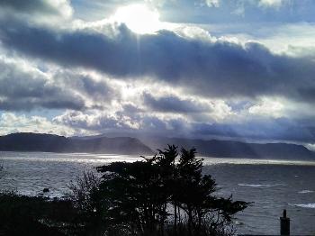Photo in dark tones showing a coastline and stormy looking sky with clouds