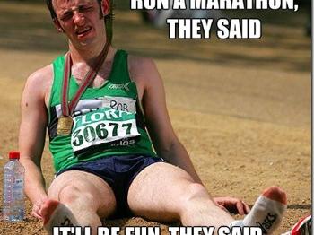 Runner laying on the ground looking very tired with a medal around his neck
