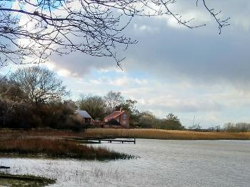 Photo of an estuary with cottage in the background 