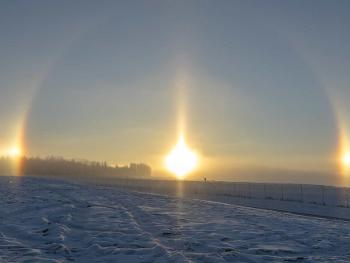 The optical illusion of 3 suns in the sky. In a snowy location. 