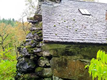 Stone cottage made out of massive lumps of rock set in a forest.