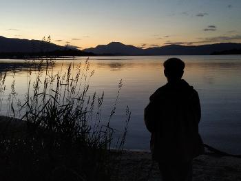Man by  Loch Lomond at sunset