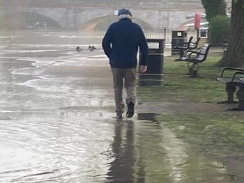 Man walking through flooded path by river