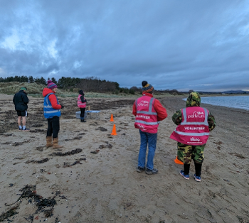 Marshals at the start of a parkrun on sand.