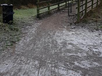 A frosty footpath leading to a footbridge crossing over a motorway