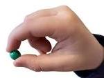 Right handed pincer grip, thumb, forefinger holding a green bead or pea. 
