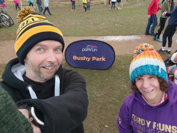 Two runners standing in front of a Bushy Park parkrun sign